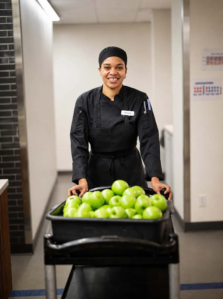 Cook smiling behind pizza station line